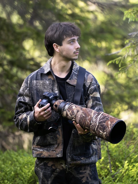 Henk Reinicke with his camera and telephoto lens in the forest.